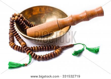 Closeup Of A Singing Bowl With Its Mallet And A Japamala On A White Background