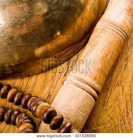 Details Of A Singing Bowl With Its Mallet And A Japamala On A Wooden Table