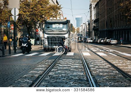 A Disabled Woman Sitting In A Wheelchair While Crossing The Street Is Having Truble Passing The Tram