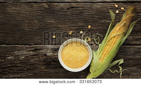 Polenta Corn Grits A Porcelain Bowl On A Wooden Table. Ears Of Corn And Pieces Of Corn Next To Bowls