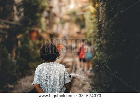 A Local Woman Living On The World Famous Train Street In Hanoi, Vietnam Waters The Plants And Her Ga