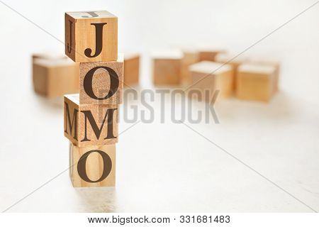 Four Wooden Cubes Arranged In Stack With Text Jomo Meaning Joy Of Missing Out On Them, Space For Tex