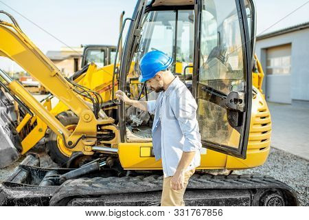 Handsome Builder Trying Escavator While Buying A New Heavy Machinery For Construction On The Open Gr