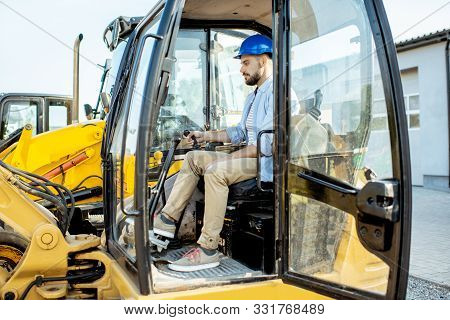 Handsome Builder Trying Escavator While Buying A New Heavy Machinery For Construction On The Open Gr