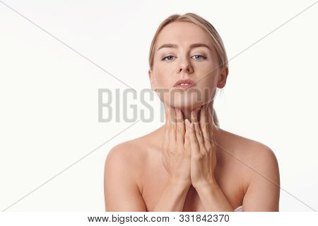 Beautiful Young Woman With Bare Shoulders Massaging Her Throat With Her Hands In The Morning To Tone