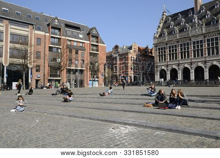Leuven, Belgium - April 1, 2019: Students Seated On Cobbled Steps At Square Outdoors The University 