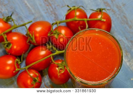 Tomato Juice With Pulp In A Glass On The Background Of Smoothly Blurred Tomatoes. Top View At An Ang