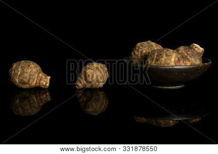 Group Of Five Whole Fresh Brown Jerusalem Artichoke In Dark Ceramic Bowl Isolated On Black Glass