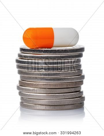 Capsule On A Stack Of Coins Isolated On White Background. Concept On The Cost Of Medication