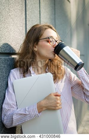Female Portrait Of Young Woman With Silver Laptop And Cup Of Coffee Waiting For A Meeting Near Dark 