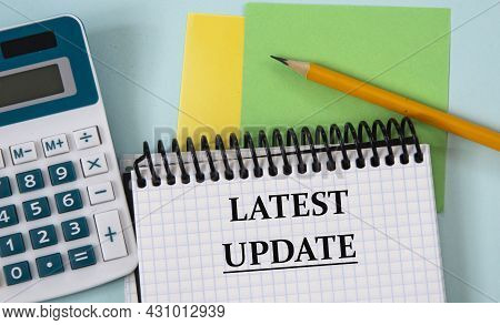 Latest Update - Words In A White Notebook On The Background Of A Calculator, Pencil, Colored Pieces 