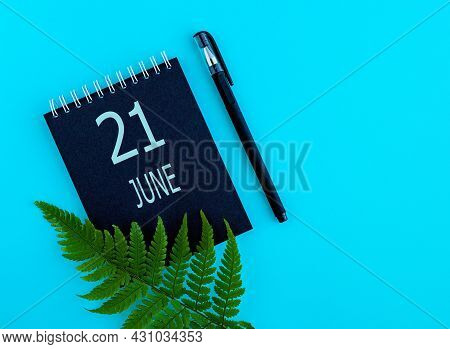June 21th. Day 21 Of Month, Calendar Date. Black Notepad Sheet, Pen, Fern Twig, On A Blue Background