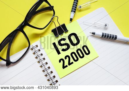 Iso22000. Text On Bright Yellow Sticker. On The Blanket. Yellow Background And Black Glasses Near Th