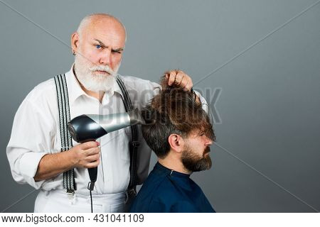 Bearded Man Getting Groomed By Hairdresser With Hair Dryer At Barbershop. Serios Hairdresser Holding