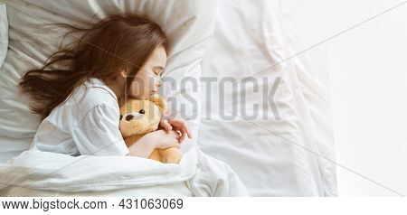 Baby Lying In Bed With Taddy Bear. Little Girl Sleeps With Knitted Toy