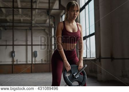 Enduring Concentrated Young Female In Sportswear Preparing For Weightlifting Workout With Heavy Barb