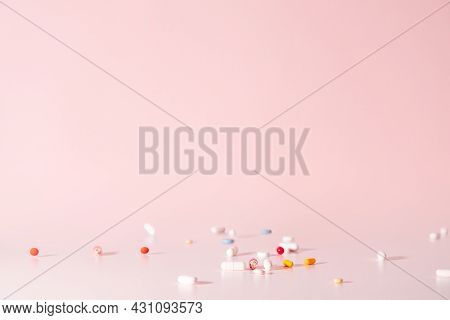 Various Colorful Pills Dropped From Top. Medicines Jumped On Table. Pink Background. Selective Focus