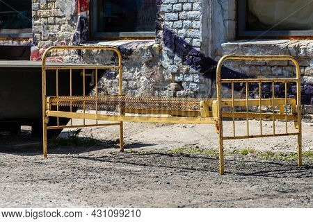 Antique Iron Bed Outside At Street On Hipster Area. Yellow Vintage Spring Metal Bed At Outdoors. Ste