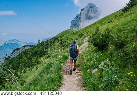 A Woman With A Backpack Stands On Top Of A Mountain, The Girl Travels To Beautiful Places, Reaching 
