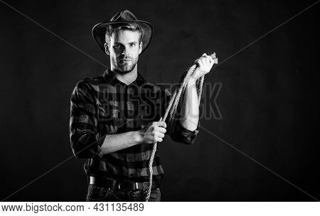 Western Life. Man Unshaven Cowboy Black Background. Man Wearing Hat Hold Rope. Lasso Tool Of America