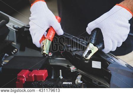 Car Mechanic Holding  Jumper Cables For Charging A Discharged Car Battery