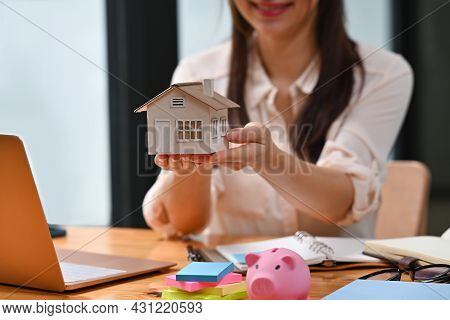 Closed Up With Real Estate Agent Holding House Model On Her Hand Presenting Possibility Of Owning Yo