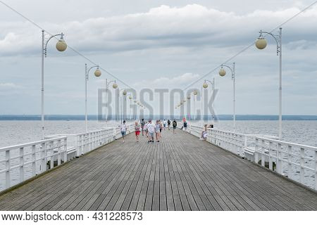 Jurata, Poland - 08.01.2021: People Walking On Ocean Pier Of Jurata On A Cloudy Summer Day On A Balt