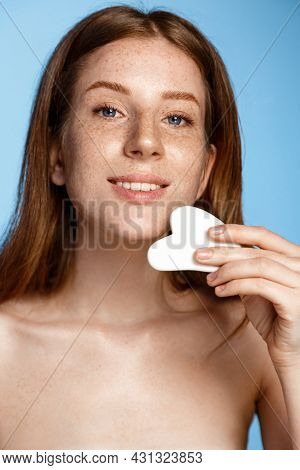 Vertical Shot Of Young Redhead Woman Does Gua Sha Massage With Tcm Scrapper, Gently Rub Facial Skin 