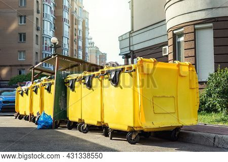 Rows Of Many Big Plastic Yellow Dumpster Cans Full Of Black Plastic Trash Litter Bags Near Residenti
