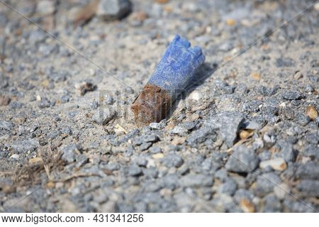 Rusty, Discharged Blue Ammunition Shell On The Gravel Ground