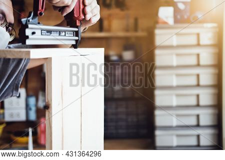 Entrepreneur Woodwork Holding A Tacker To Assemble The Wood Pieces As The Customer Ordered.