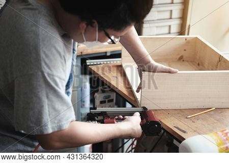 Entrepreneur Woodwork Holding A Tacker To Assemble The Wood Pieces As The Customer Ordered.
