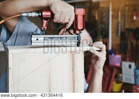 Entrepreneur Woodwork Holding A Tacker To Assemble The Wood Pieces As The Customer Ordered.