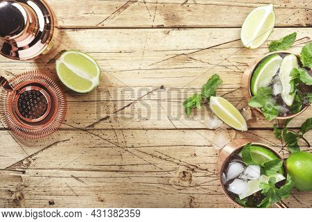Moscow Mule Cocktails In Copper Mug With Lime, Ice, Ginger Beer, Vodka And Mint. Wooden Background, 