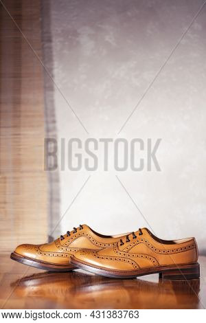 Pair Of Full Broggued Tan Leather Oxfords Broggued Shoes Against White Wall Background