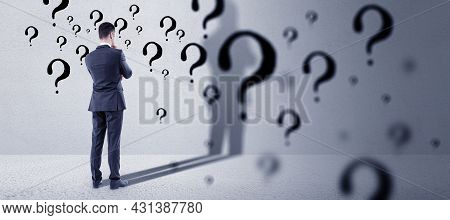 Thinking Young European Businessman Standing In Concete Interior With Question Mark Sketch. Solution