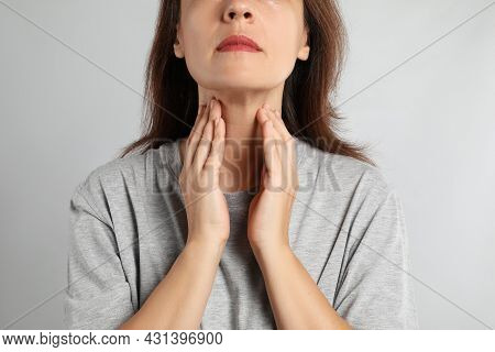 Mature Woman Doing Thyroid Self Examination On Light Background, Closeup