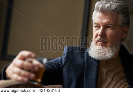 Confident Middle Aged Business Man Holding Glass Of Alcohol Scotch Whiskey In His Hand While Relaxin