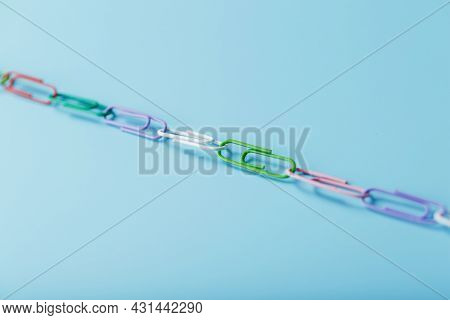 Interlocked Colored Paper Clips In A Line On A Blue Background With Free Space