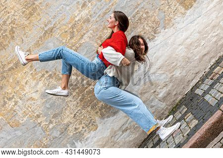 Funny Teenager Carrying Her Best Friend Piggyback On The Pavement At The Old Wall, Positive Emotions