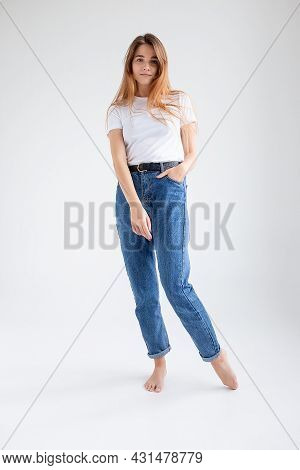 Young Attractive Caucasian Woman With Long Hair In T-shirt And Blue Jeans Isolated On White Studio B
