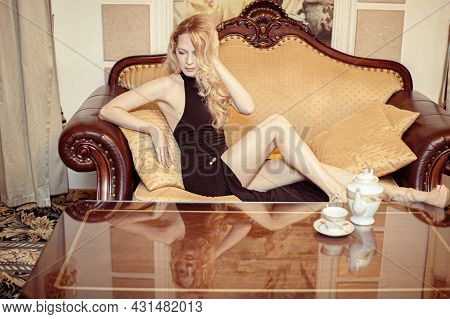 Beautiful Young Adult Blond Woman Sitting On Sofa