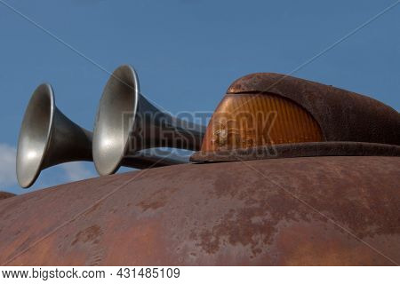 Close-up Of The Boundary Light And Horn Of An Old Rusty Scraper Wagon With Blue Sky Background