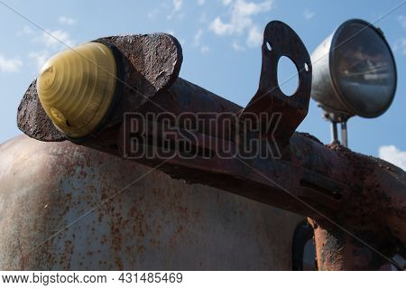 Close-up Of The Boundary Light And Horn Of An Old Rusty Scraper Wagon With Blue Sky Background