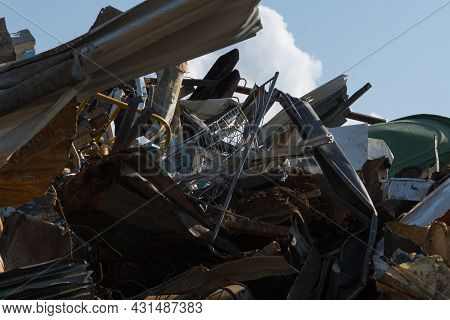 Scrap Iron And Metal At A Scrap Yard Against Blue Sky With White Clouds