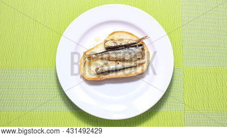 Fish Sprats On A Piece Of White Bread On A Plate. Top View.