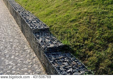 Gabion Granite Wall. Wire Baskets Filled With Stones. On The Edge Of The Sidewalk, In The Bend Of Th
