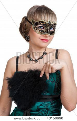 สาวสวยในชุดราตรีสีเขียวกับสร้อยคอและต่างหูในคาร์นิวัลหน้ากาก hodling พัดลม
