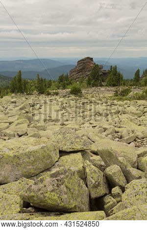 Large Kurum Stones Lie In The Forest In The Mountains, Stones Covered With Moss, Against The Backgro