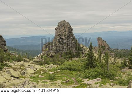 Large Kurum Stones Lie In The Forest In The Mountains, Stones Covered With Moss, Against The Backgro